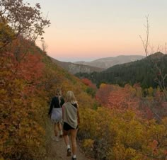 two women walking up a trail in the mountains at sunset or dawn with colorful foliage