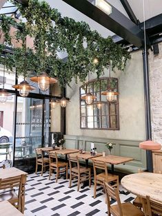 the interior of a restaurant with tables, chairs and plants hanging from the ceiling above them