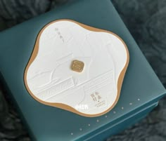 a white and gold plate sitting on top of a blue box