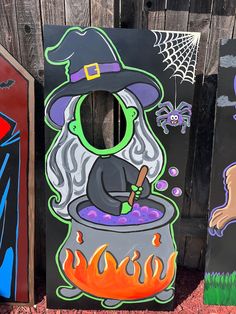 three painted wooden boards with witches and pumpkins on them in front of a fence