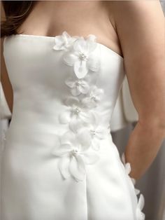 a woman wearing a white dress with flowers on the front and back of her dress