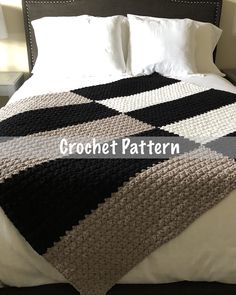 a crocheted blanket on top of a bed with white sheets and black pillows