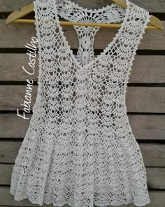 a crocheted top hanging on a wooden hanger