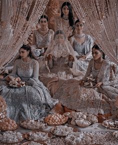 a group of women sitting next to each other on top of a floor covered in food