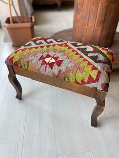 a wooden bench sitting on top of a white floor next to a potted plant