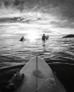 two surfers in the ocean with their surfboards