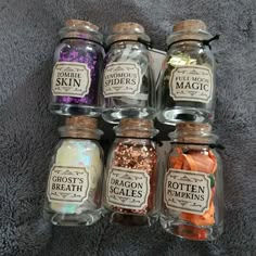 six glass jars filled with different types of spices on a gray blanket, each containing their own label