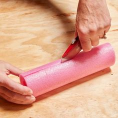 a person is using a pen to write on a pink object