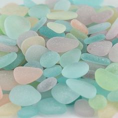 small pieces of sea glass sitting on top of each other in pastel blue, pink and green colors