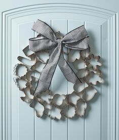 a metal wreath hanging on the side of a white door with a black and white bow