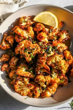 roasted cauliflower with lemon wedges and parsley on the side in a bowl