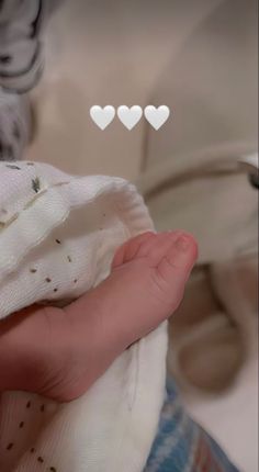 a baby's hand holding a white cloth with hearts above it and the words i love you