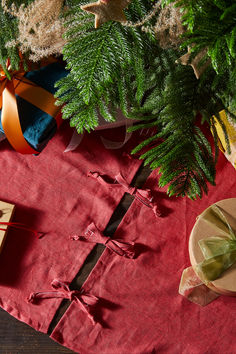 a red table cloth with christmas decorations on it and presents in front of the tree