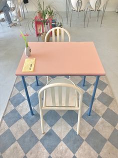 three chairs and a table in a room with checkered flooring on the floor