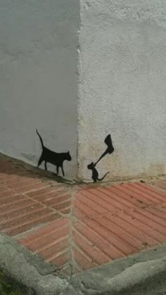 a cat and dog are painted on the side of a building with an arrow in it's mouth