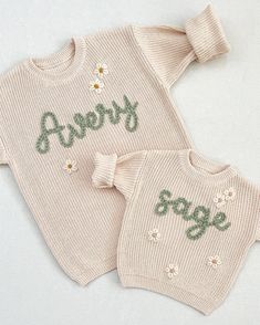 two knitted sweaters with flowers and the words avery on them are sitting next to each other