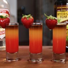 three glasses filled with drinks sitting on top of a table