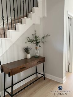 a wooden table sitting under a stair case next to a bannister with plants on it