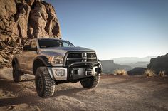 a large truck is parked on the side of a mountain road in front of some rocks