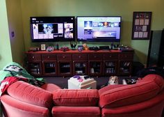 a living room with two red couches and a flat screen tv on the wall