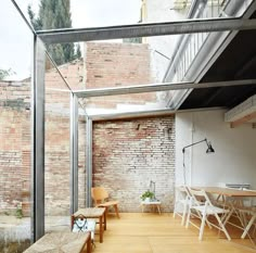 the interior of an apartment with exposed brick walls and wooden flooring, along with white chairs and tables