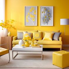 a living room with yellow and gray furniture in the corner, two paintings on the wall