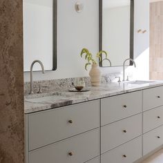 a bathroom with marble counter tops and double sinks in the middle, two mirrors above them