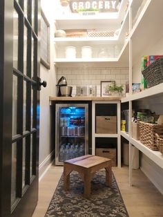 a small kitchen with a coffee table in the center and shelves full of bottles on either side