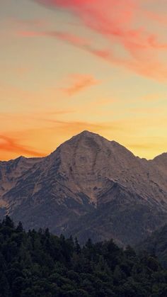 the mountains are covered in trees as the sun sets