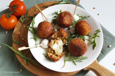 several appetizers are on a white plate with tomatoes and breadsticks next to them