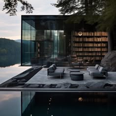 an outdoor living area next to a body of water with bookshelves in the background