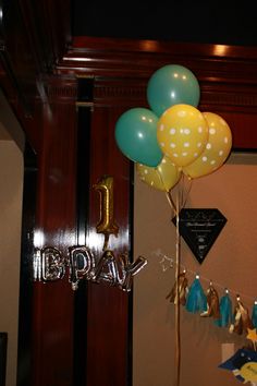 the first birthday balloons are hanging on the wall