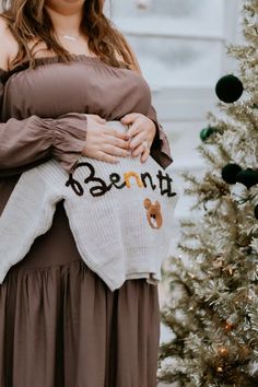 a woman in a dress is holding a teddy bear sweater with the word parent written on it