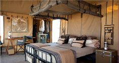 a bed sitting inside of a tent next to a desk with a laptop on it