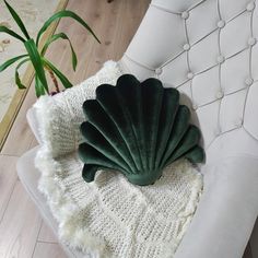 a white chair with a green shell shaped pillow on it