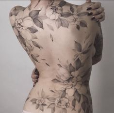 a woman with tattoos on her back posing for the camera and holding her hand up to her chest