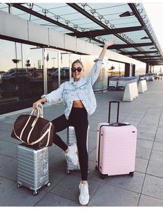 a woman is posing with her luggage at the airport