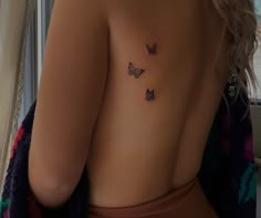 a woman's back with three butterflies tattoo on her left shoulder and right breast