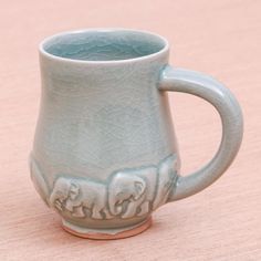 a ceramic mug with elephants on it sitting on a table