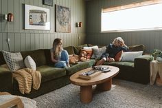 two women sitting on couches in a living room with green walls and rugs