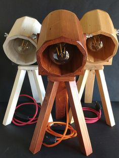 three wooden lamps sitting next to each other on top of a black surface with wires coming out of them