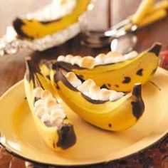 two bananas with chocolate and marshmallows on them sitting on a yellow plate