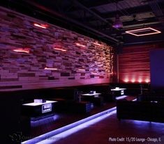 a dimly lit room with couches and tables on the floor in front of a brick wall