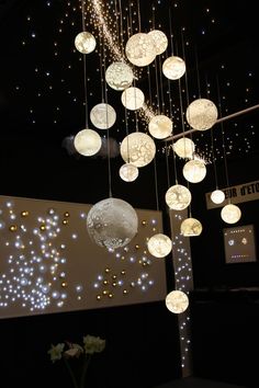 a bunch of lights hanging from the ceiling in a room with black walls and flooring