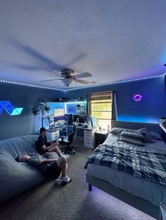 a man sitting on a bean bag chair in a bedroom next to a computer desk