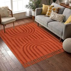 a living room with a gray couch and orange rug