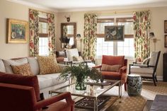 a living room filled with furniture and windows covered in floral draping on the walls