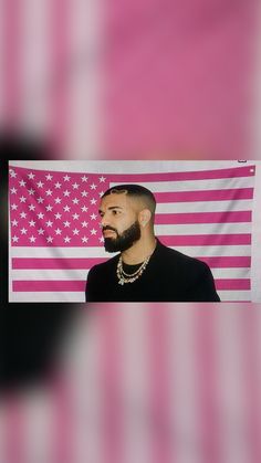 a man with a beard standing in front of an american flag and wearing a necklace