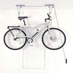 a bicycle mounted to the side of a white wall with bars on it's sides