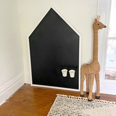 a giraffe statue next to two cups in front of a black and white wall